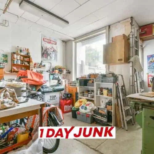 Cluttered workshop filled with tools, boxes, and supplies before professional junk removal service by 1DayJunk