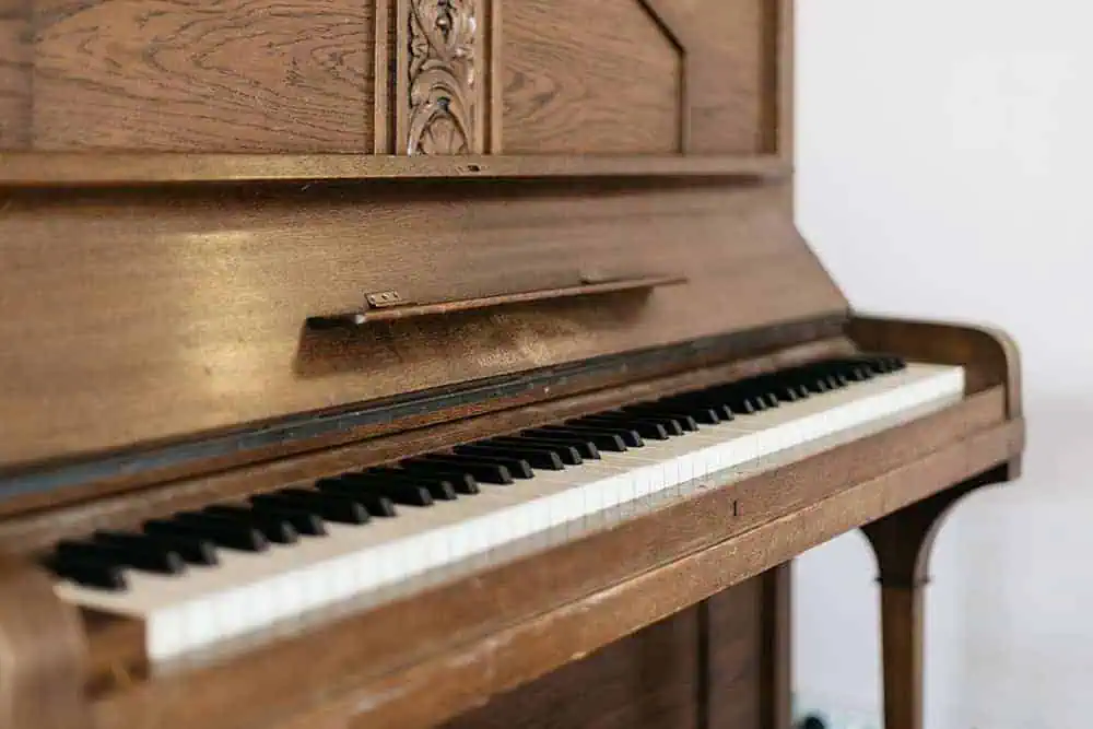 Close-up of a vintage upright piano with polished wooden finish and clean black and white keys.
